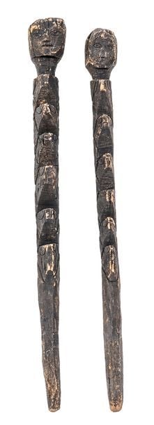 Deux piquets de propriété de terrain en bois sculpté et gravé en épis surmontés de têtes anthropomorphe