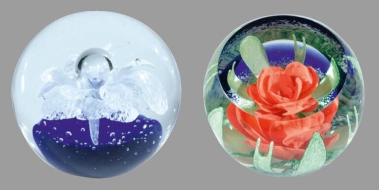 Deux presse-papiers à motif de fleur en trois dimensions: une blanche à coeur formant une bulle et une rouge sur fond bleu et granité à fenêtre obliqu