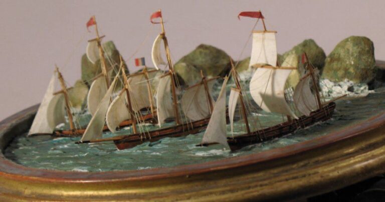 DIORAMA constitué de trois petits trois-mâts et d'une barque sur une mer en mastic peint et près de rochers les voiles sont en ivoire et les coques en bois peint et vern