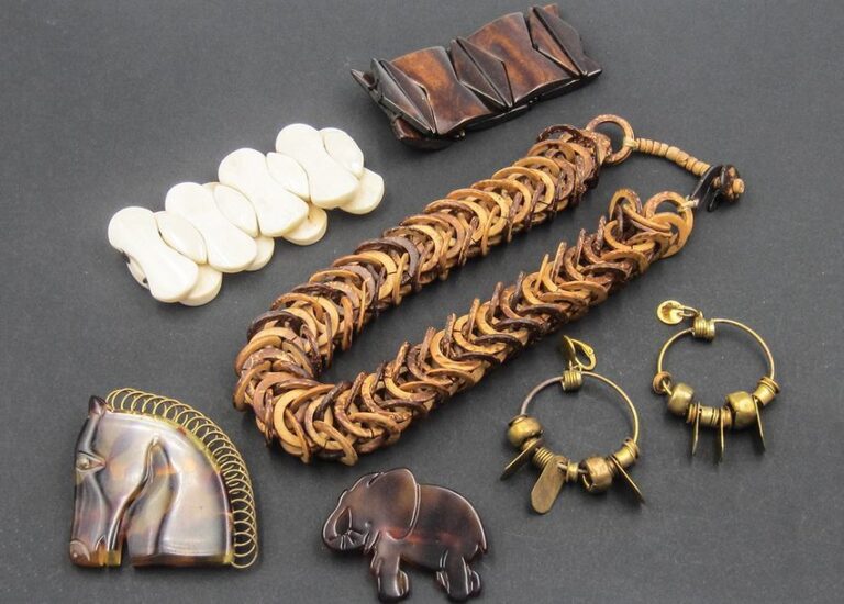 Ensemble «Afrique» comprenant: collier à maille façon écorce, deux bracelets façon ivoire et bois, deux broches façon écaille de tortue en forme d'éléphant et tête de cheval, paire de pendants d'oreilles à anneaux et breloques en laito