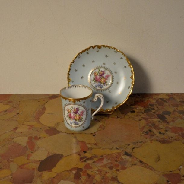 Ensemble de 12 tasses à café en porcelaine de Limoges à décor de fleurs en réserve sur fond ble
