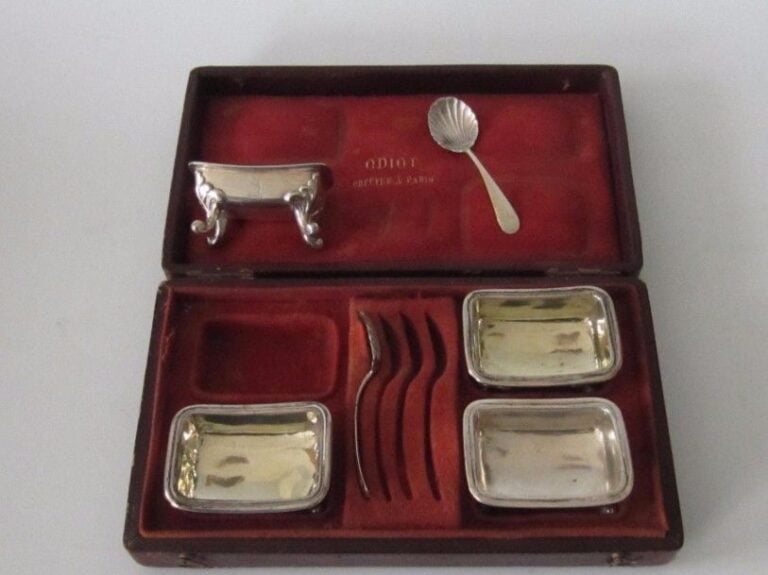 Ensemble de 4 salières armoriées en argent, reposant sur quatre petits pieds à enroulements à attaches feuillagées et deux pelles à sel en argent (même crest que sur les salières : couronne surmontée d’un cerf