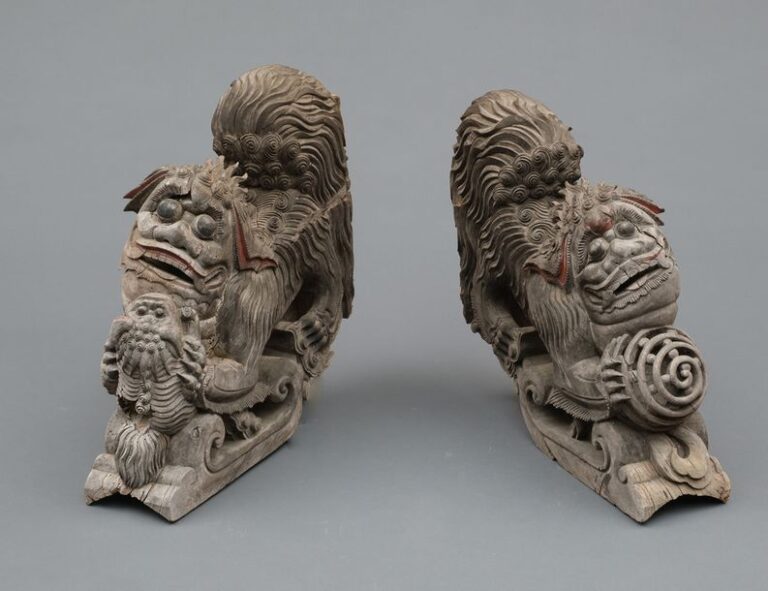 Ensemble de deux colonnes en bois en provenance de Ky?sh?, à décors gravés de lions chinois (karashishi): l’une représentant un lion male sa patte reposant sur une balle, et l’autre une lionne jouant avec ses petit