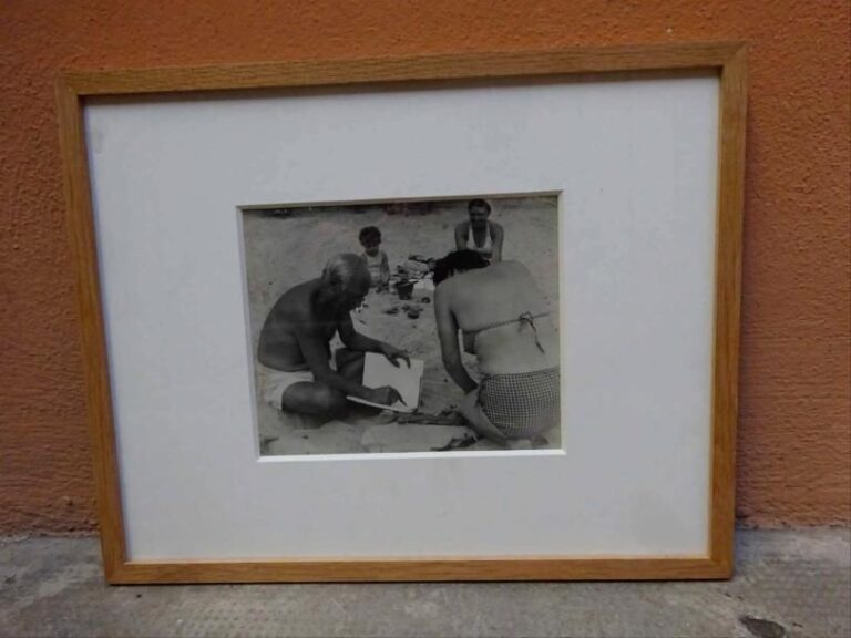 Ervin MARTON (1912-1968) Portrait de Pablo Picasso  à la plage dédicaçant un ouvrage Photographie argentique en noir et blanc  Cachet du photographe au revers de la photographie (laissé visible): "Marton 11, Rue Bellier-Dedouvre Paris XIIIe" 17,5 x 21,7 cm (à vue)