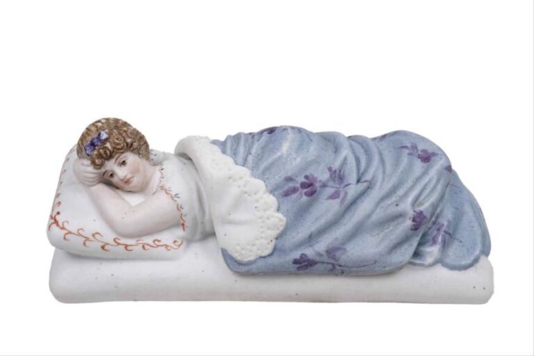 Figure érotique en biscuit de porcelaine polychrome représentant une femme allongée à demi-nue sur un lit, avec sa couverture amovibl