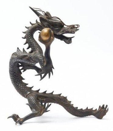 Figurine de bronze représentant un mince dragon, sa patte droite tenant une perle, également en bronz
