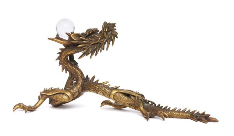 Figurine en cuivre jaune figurant un dragon tenant une perle de verre dans ses griffe