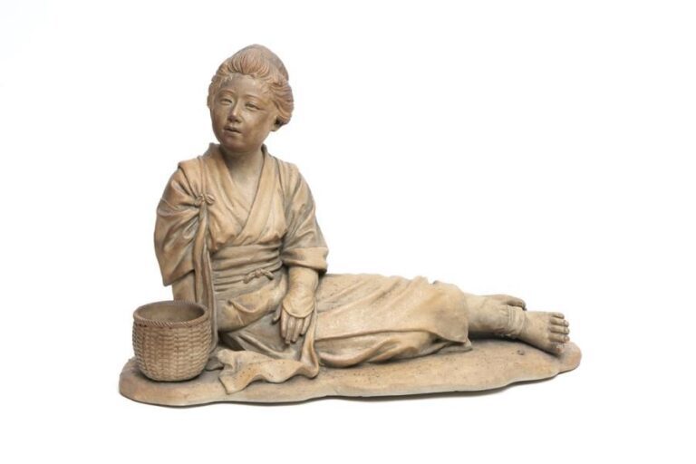 Figurine en porcelaine tendre marron clair figurant une jeune fermière allongée près d'un panier à fleu