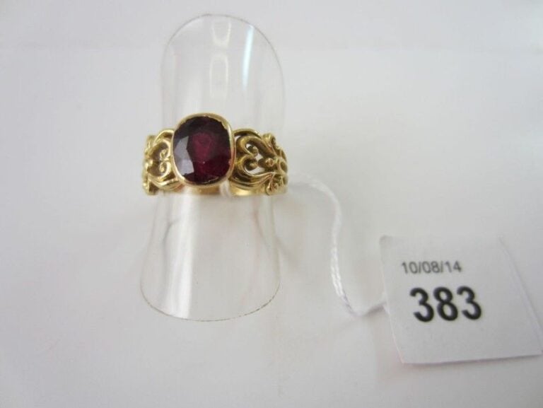 Fine BAGUE en or jaune (750 millièmes) ajouré à motifs de volute serti d'un grenat (chocs