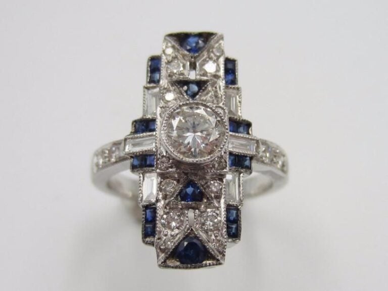 Fine BAGUE rectangulaire en or gris (750 millièmes) serti de diamants taille brillant et baguettes et saphirs calibrés, à motifs géométrique