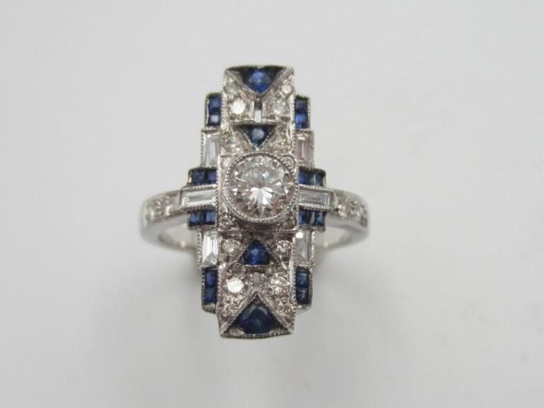 Fine BAGUE rectangulaire en or gris (750 millièmes) serti de diamants taille brillant et baguettes et saphirs calibrés, à motifs géométrique