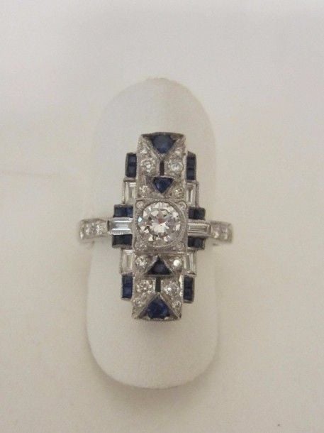 Fine BAGUE rectangulaire en or gris (750 millièmes) serti de diamants taille brillant et baguettes et saphirs calibrés, à motifs géométrique