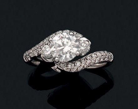 Fine BAGUE sinueuse en or gris (750 millièmes) serti d'un diamant taille brillant pesant 1,00 carat épaulé de deux pavages de diamants et deux diamants plus important