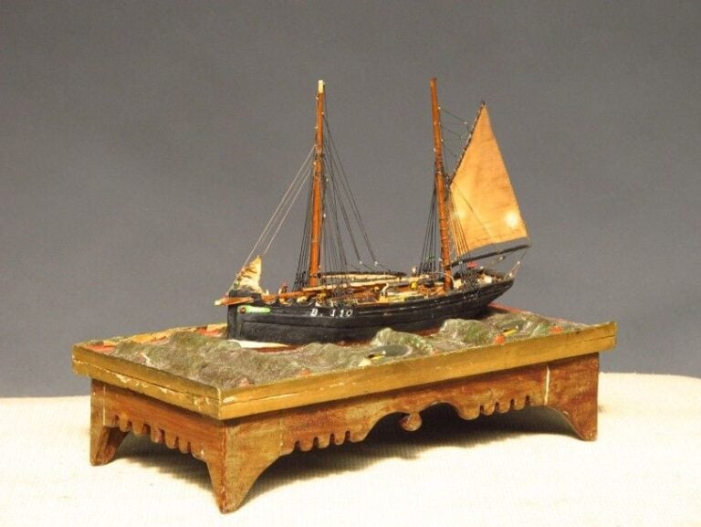 Fine maquette d'un bateau de pêche présentée en «situation», entourée de dauphins Art populaire, début du XXe siècle Vitrine de protection 18 x 38 cm
