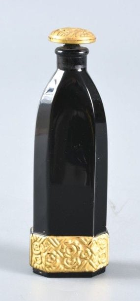 Flacon à parfum en verre noir moulé à pans; bandeau à la base et bouchon moulés et dorés à motif de fleur