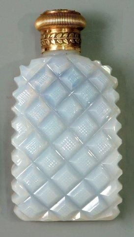 Flacon à sels arqué en opaline de cristal savonneuse taillé sur une face à diamants guillochés; bouchon à vis en or ouvragé à deux ton