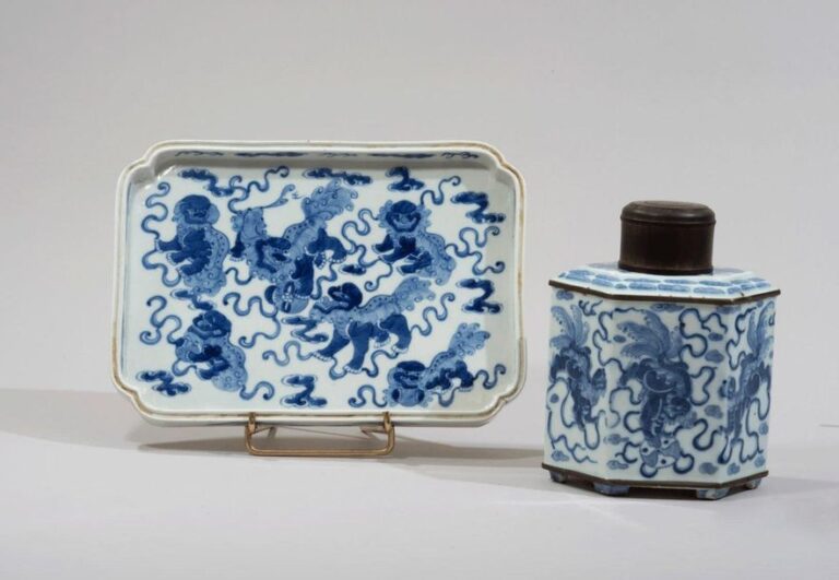 Flacon à thé et plateau en porcelaine décorée en bleu sous couverte de chimères jouant avec des balles de ruban parmi les nuage
