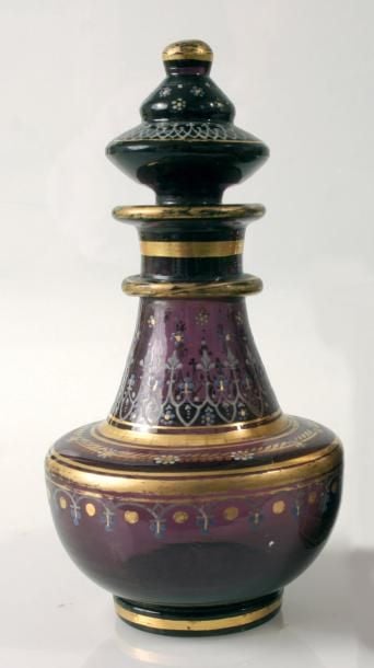Flacon caréné à talon et cordon de col en cristal améthyste à décor Desvignes de guirlande de fleurettes blanches et dorées et de feuillage doré et rouge stylisés, de bandeau d'arcature fleurie blanche et bleue, de semis de myosotis bleus et de filets dorés; bouchon à bandeau ogival blanc et myosotis bleu
