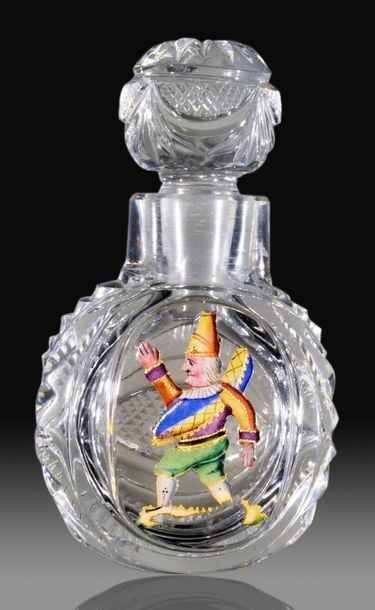 Flacon en cristal taillé et son bouchon boule à motifs rayonnants, draperies, crantage et navette diamantée, orné d'un motif émaillé sur paillon d'or représentant Polichinelle, personnage de la Comédia del Art
