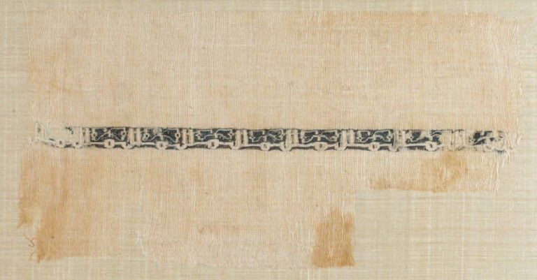 FRAGMENT DE TAPISSERIE Bandeau d'une ligne d'inscriptions coufiques répétitives blanches en réserve sur toile de li