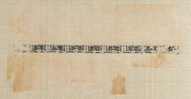FRAGMENT DE TAPISSERIE Bandeau d'une ligne d'inscriptions coufiques répétitives blanches en réserve sur toile de li