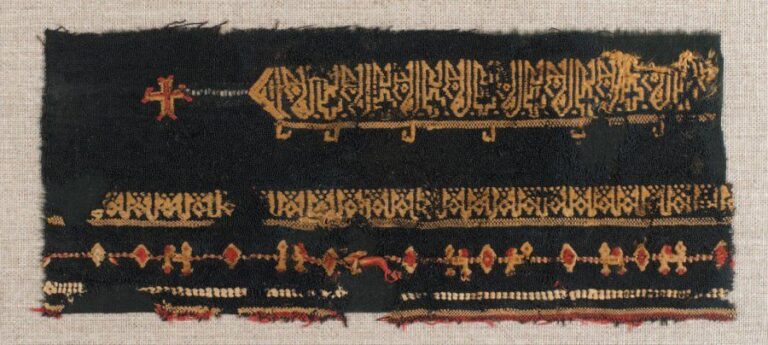 FRAGMENT DE TAPISSERIE Fragment de toile noire orné de motifs linéaires et de deux lignes d'inscriptions coufiques blanches, l'une prolongée par une croi