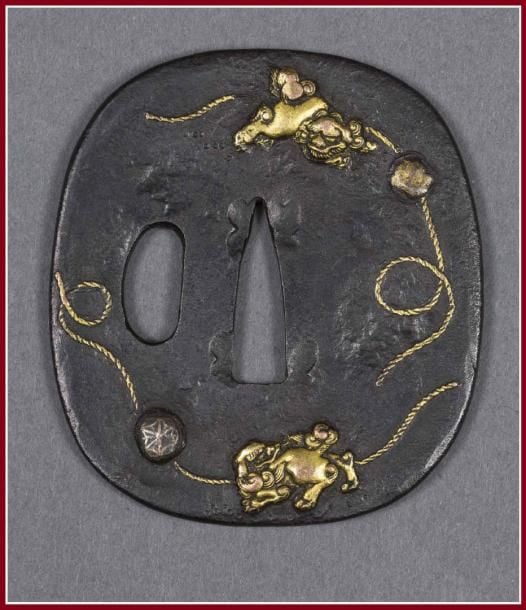 GARDE DE SABRE DE SAMOURAI A DECOR DE SHISHI, TSUBA Japon, Epoque XIXe siècle De forme intermédiaire (tata maru gata), à décor de deux chiots (shishi) aux rubans et aux balles, l'un des rubans se prolongeant au rever