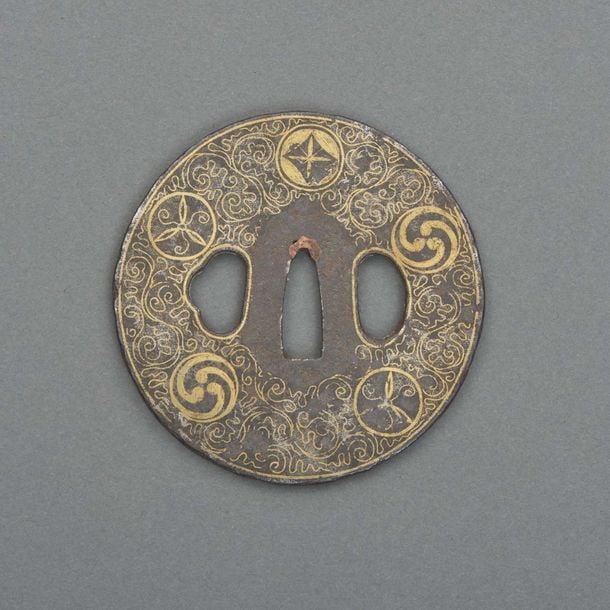 Garde de sabre (tsuba) de forme ronde incrusté d’or garni de volutes et emblèmes familiaux (mon) varié