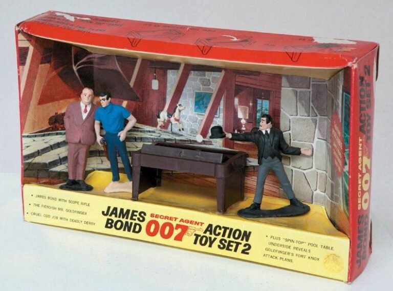 Gilbert - Goldfinger Action Toy Set 2 Occasion en Boîte England, 1965 Playset reprenant une scène du film «Goldfinger» - Figurines de 10 cm en plastique de James Bond, Od Jobb et Goldfinger, le billard cache les plans de l'attaque de fort Knox sous son recto, le tout est présenté dans une boîte reprenant le décor intérieur de la maison