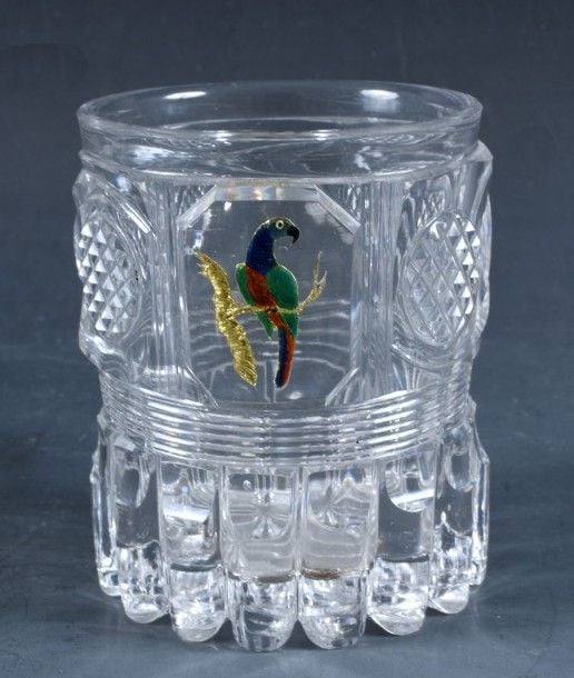 Gobelet en cristal taillé à côtes torses et quatres pastilles diamantées, bandeau de filets biseautés et côte de bambou à la base; décor émaillé polychrome sur paillon d'or représentant un perroque