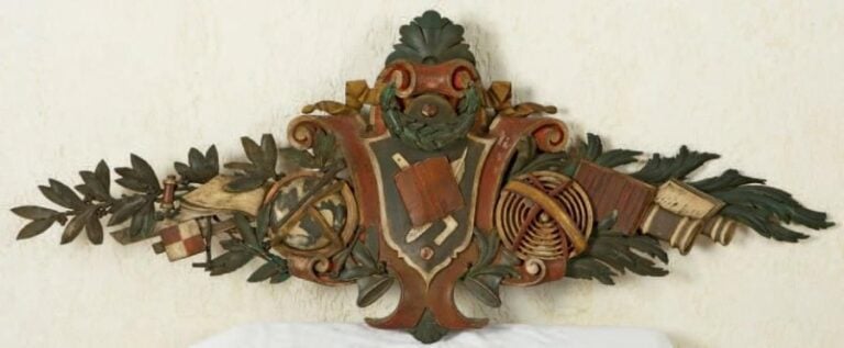 Grand bas-relief en bois sculpté et polychromé représentant un globe, un livre, une planisphère avec des branches de laurie