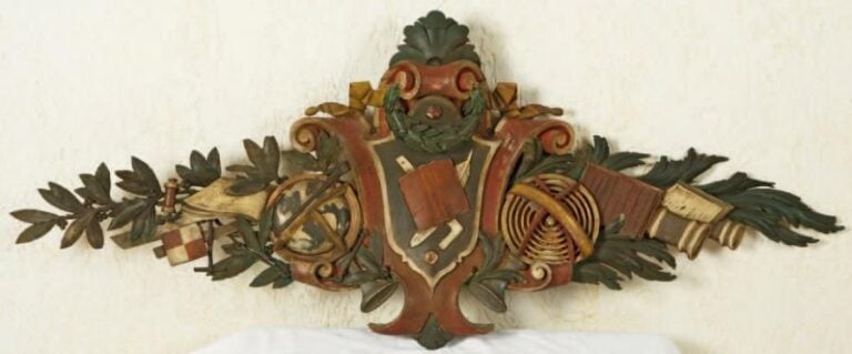 Grand bas-relief en bois sculpté et polychromé représentant un globe, un livre, une planisphère avec des branches de laurie