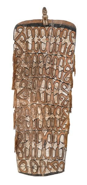 Grand bouclier en bois sculpté polychrome surmonté d'une figure masculine, fibres végétale