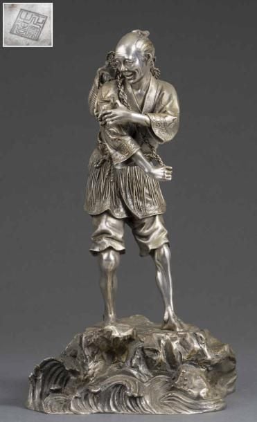 GRAND OKIMONO EN BRONZE A PATINE ARGENTEE A L'EFFIGIE D'UN PECHEUR DE CRABES Japon, Epoque XXe siècle, Période Meiji / Taisho Le pêcheur est représenté debout sur une base rocheuse ceinte de vagues agitée