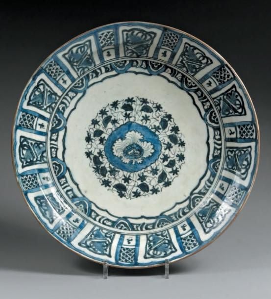 Grand plat de type kraak Céramique à décor bleu blanc peint sous glaçure transparente Ce grand plat présente un médaillon central décoré de fleurs sur un semis végétal et un décor dit Kraak, composé de compartiments ornés de motifs floraux sur le marl