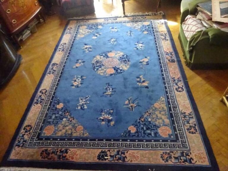 GRAND TAPIS CHINOIS EN LAINE DANS LES TONS BLEUS ET ROUGE Chine, Epoque XXe siècle Couleurs vives, franges courant sur le pourtour, beau décor floral stylisé dont un joli « mon » centra