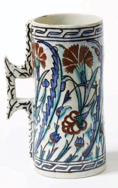 Grande chope Iznik Céramique siliceuse à décor peint en rouge, vert, bleu, noir et blanc sous glaçure incolore transparente Turquie, Iznik, circa 1600, Empire Ottoman Hauteur: 25,5 cm Elle est décorée d'oeillets et de feuilles saz sur la pans