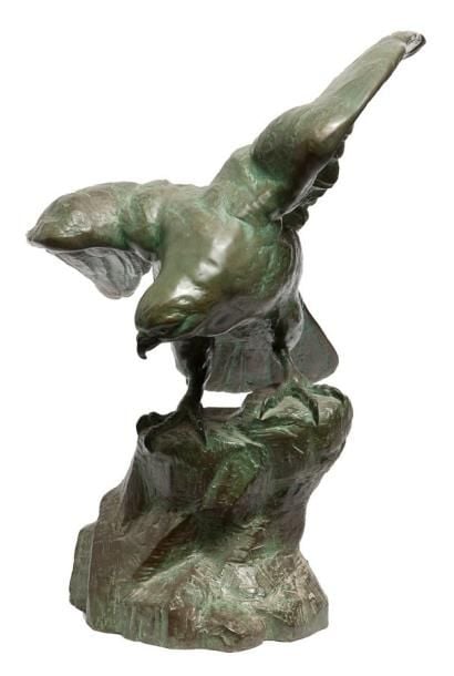 Grande figurine en bronze à patine verte représentant un oiseau de proie en train de se poser sur un rocher, les ailes entrouverte