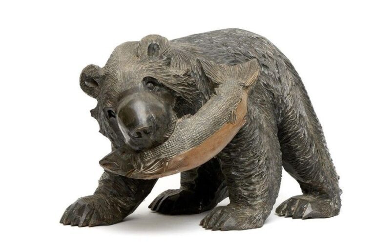 Grande statuette en bois sculpté figurant un ours debout et tenant dans sa gueule un saumo