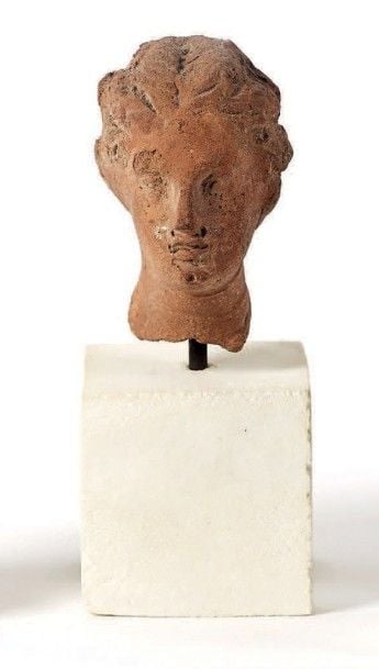 Grande tête féminine dont la coiffure en cote de melon est rassemblée par un chignon au niveau de la nuqu