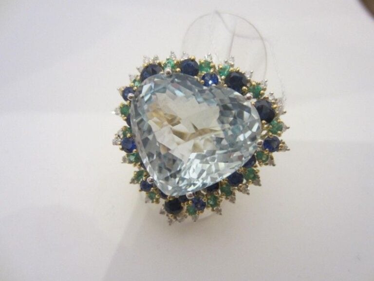 Important BAGUE en or jaune et or gris (750 millièmes) serti d’une aigue-marine facettée de forme coeur entouré de lignes de saphirs, émeraudes et diamants taille brillants