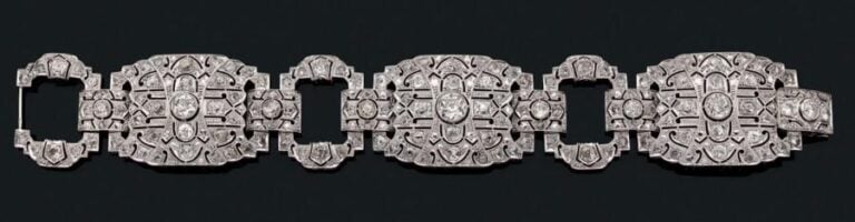 Important BRACELET en platine (900 millièmes) ciselé et ajouré, à motifs géométriques, serti de diamants taillés en rose et taille ancienne dont trois plus importan