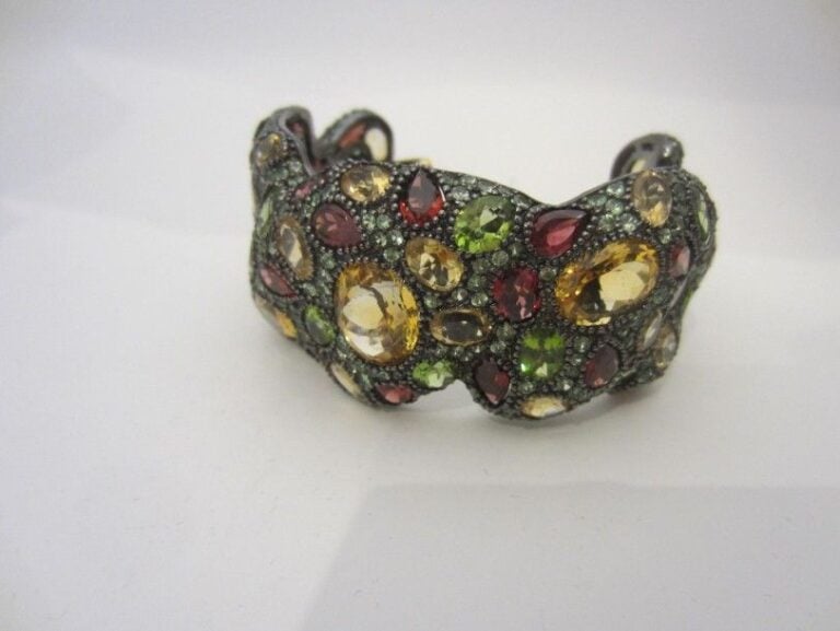 Important BRACELET jonc ouvert en or jaune (750 millièmes) et argent noirci (800 millièmes) entièrement pavé de pierres précieuses de couleur et de forme diverses Chaînette de sécurité