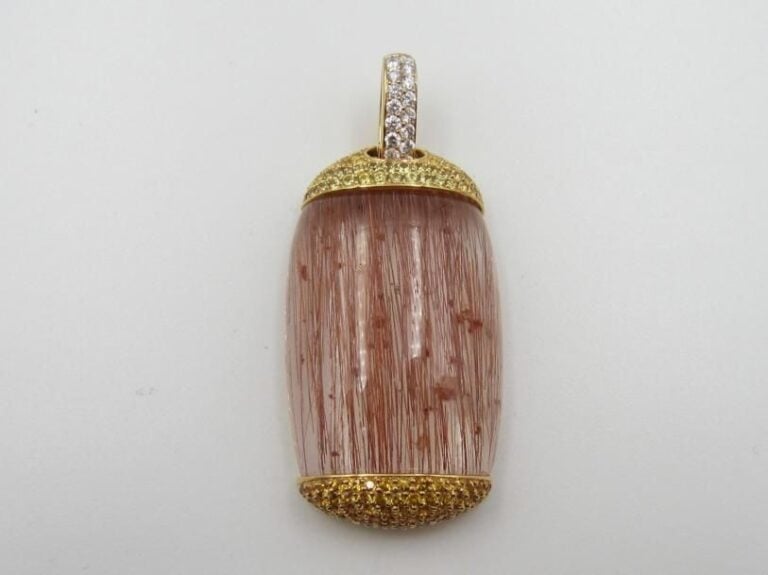 Important PENDENTIF en or jaune (750 millièmes) serti d’un important quartz rutilé pesant 95 carats environ, épaulé de pavages de saphirs jaunes et diamants taille brillant        Bélière articulée ouvrante              Long        : 5,7 cm        Poids brut : 33,7 g