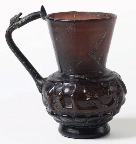 Important pichet en verre à frise calligraphique Verre aubergine à décor moulé Iran, Xe - XIIe siècle Hauteur: 14,5 cm Cet important pichet en verre aubergine à base de manganèse est un exemple de très grande qualité de décor calligraphique moul