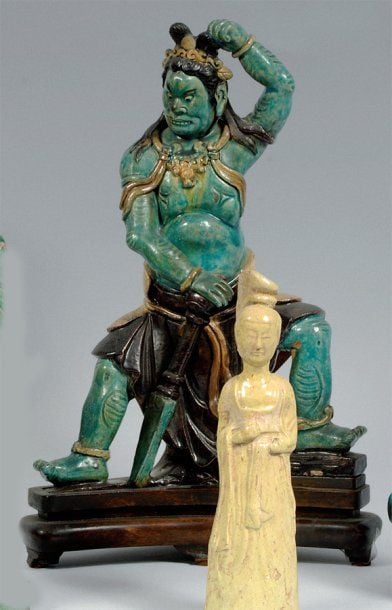 Important sujet en céramique émaillée bleu, jaune et manganèse, représentant une divinité gardienne à l'aspect terrifiant, tenant son chignon, une main posée sur un phurb