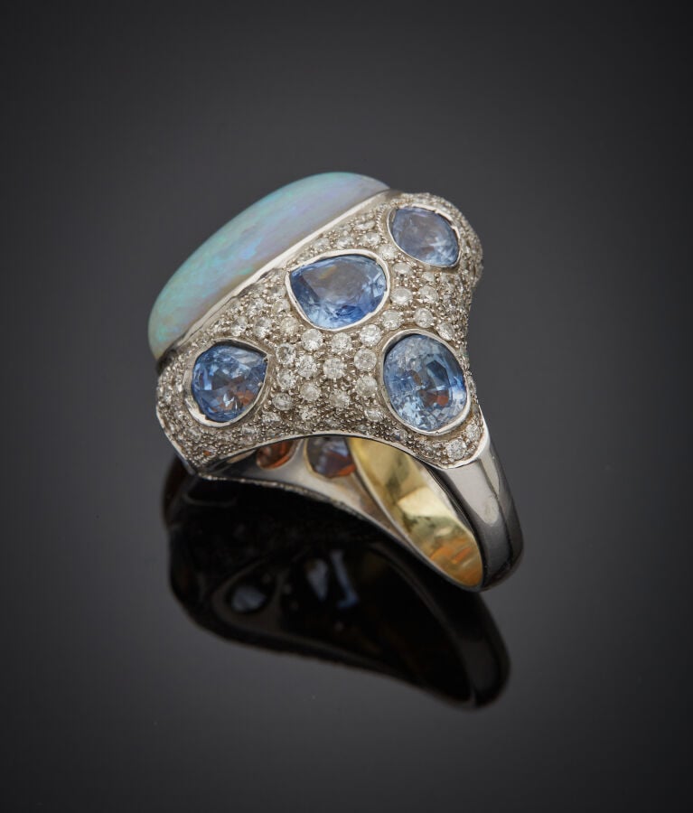 Importante BAGUE en or gris (750‰), orné d'une opale de forme ovale (fêles), en…