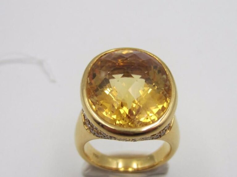 Importante BAGUE en or jaune (750 millièmes) ajouré à motifs de volutes serti de diamants surmontée d’une citrine de forme oval