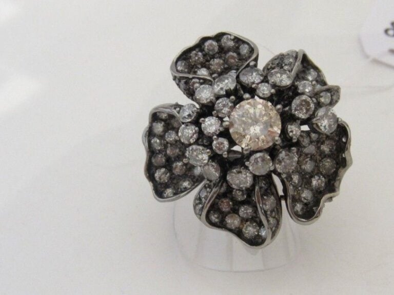 Importante BAGUE « fleur » en or noirci (750 millièmes)  ajouré, pavé de diamants taille brillant blancs et bruns dont un, au centre, plus important, pesant 1,3 carat en