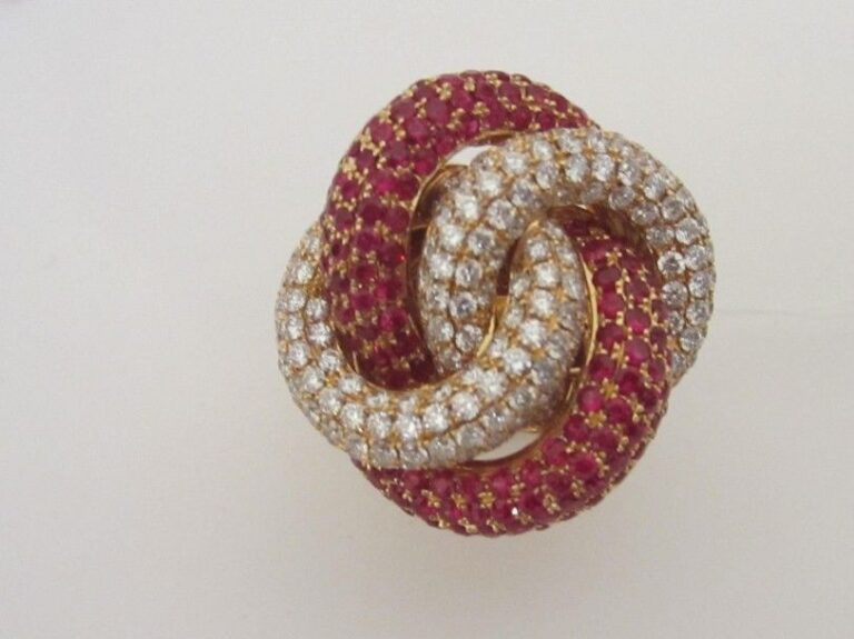 Importante BAGUE «noeud stylisé» en or jaune (750 millièmes) pavé de rubis ronds et diamants taille brillan